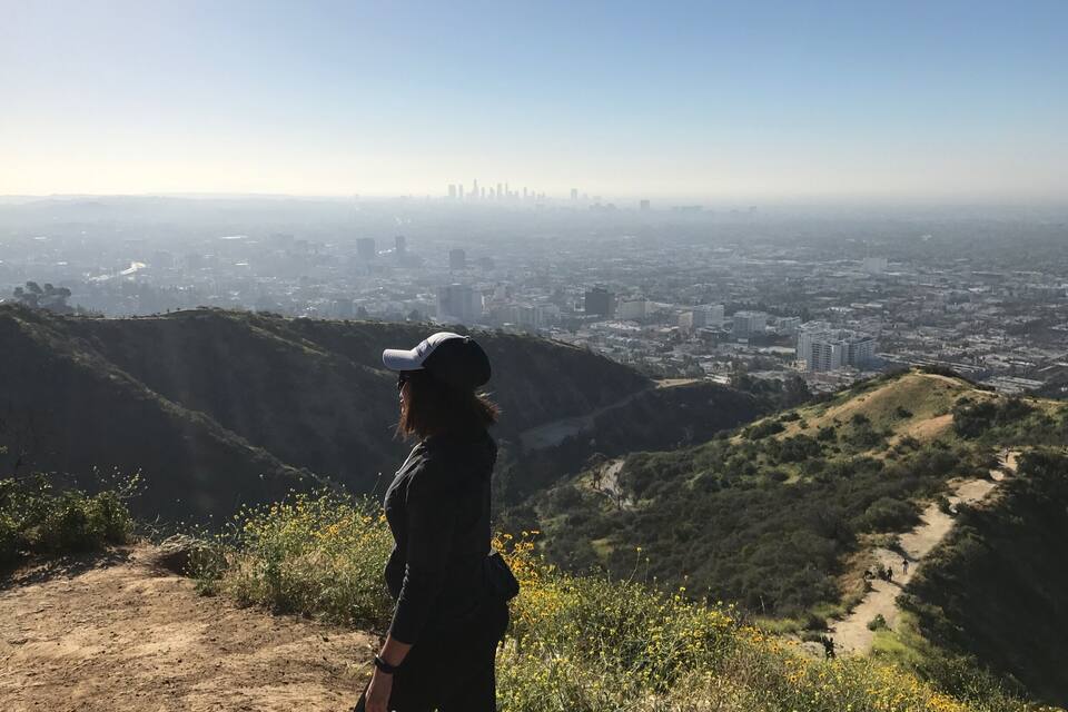 Une personne se tient sur une colline, d’où elle a une vue panoramique sur la ville.