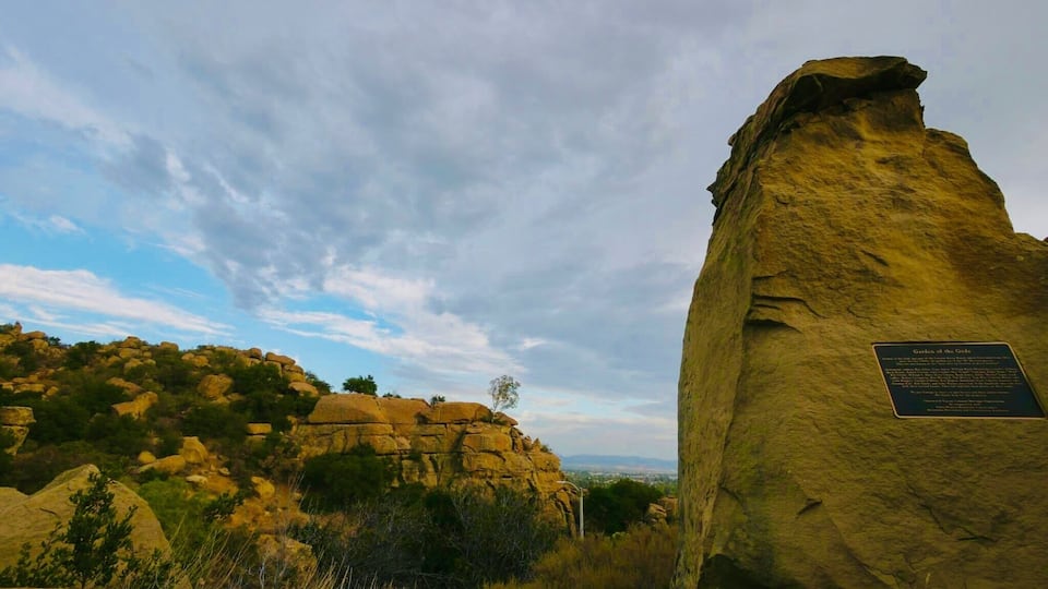 A large rock formation with a plaque, surrounded by smaller rocks and sparse vegetation.