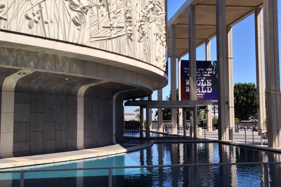 Um edifício moderno com piscina e uma placa que diz 'Ole World Here'.