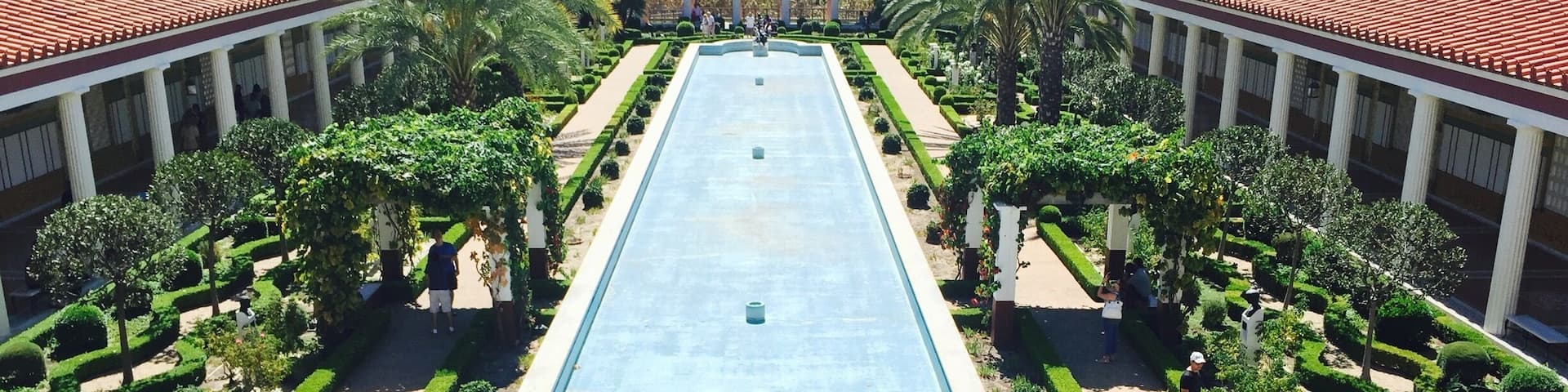 A large rectangular pool with a fountain in the center, surrounded by manicured gardens and a pavilion.