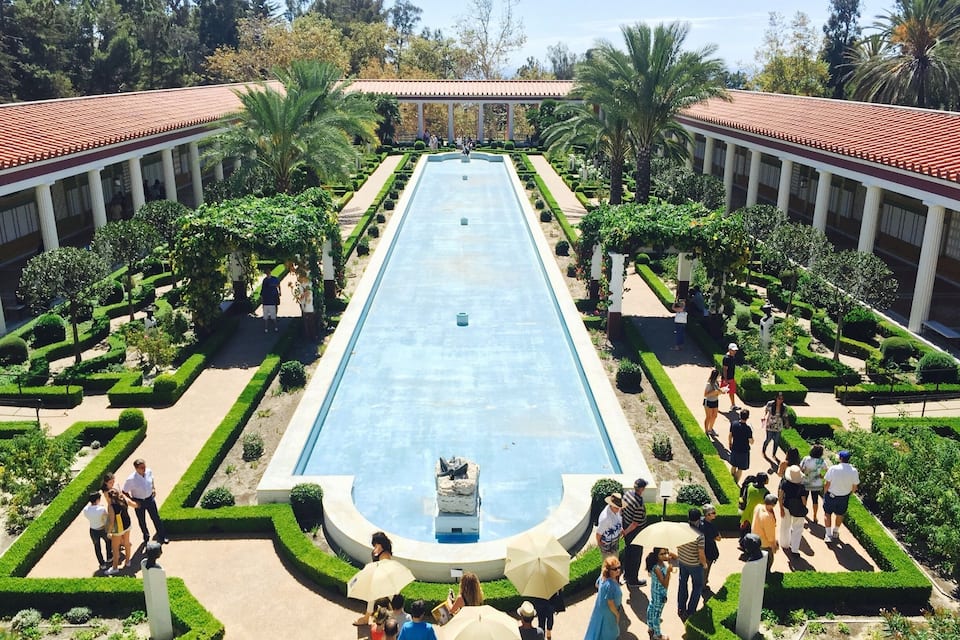 A large rectangular pool with a fountain in the center, surrounded by manicured gardens and a pavilion.
