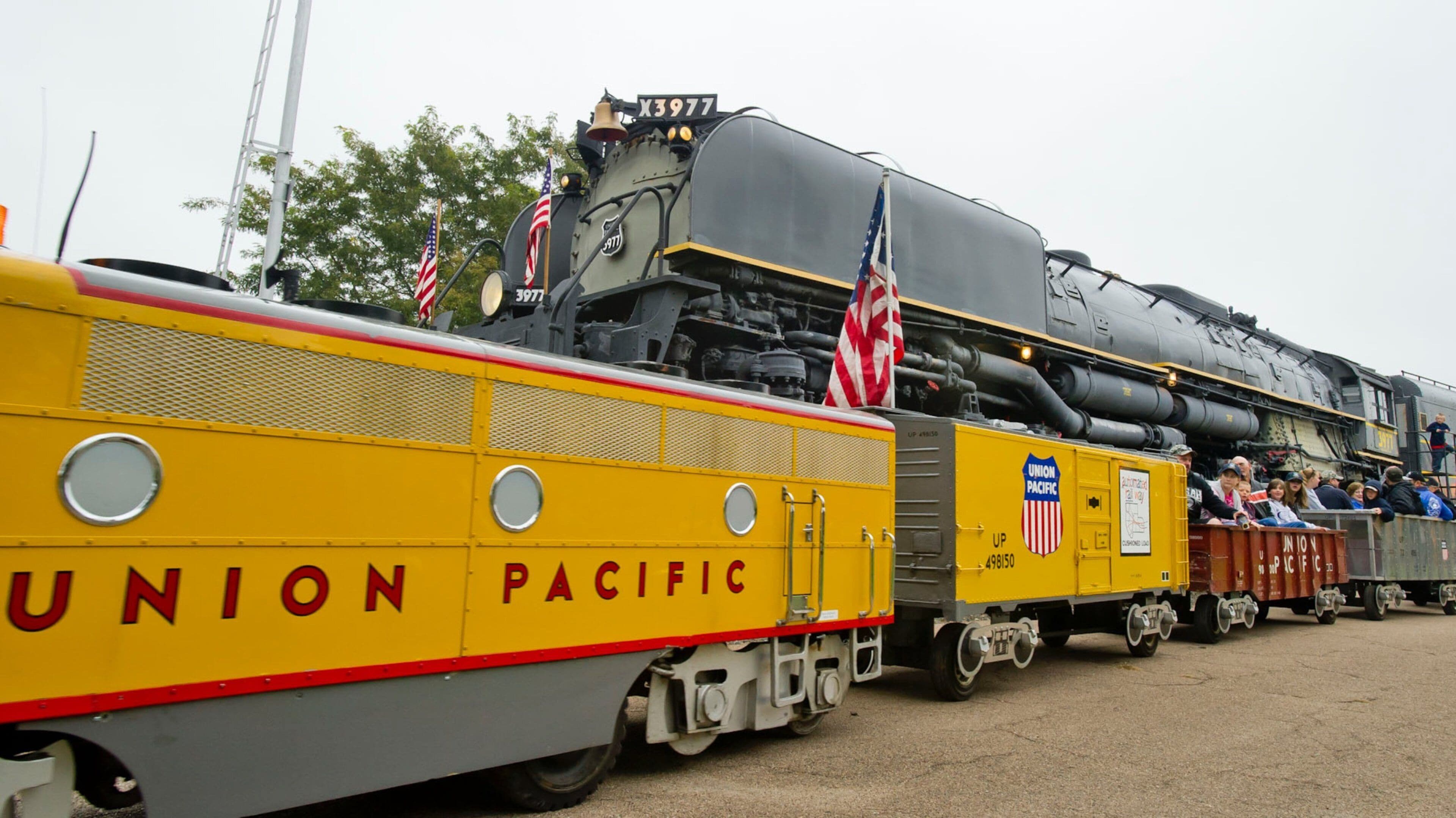 A Union Pacific train with a yellow caboose and American flags.