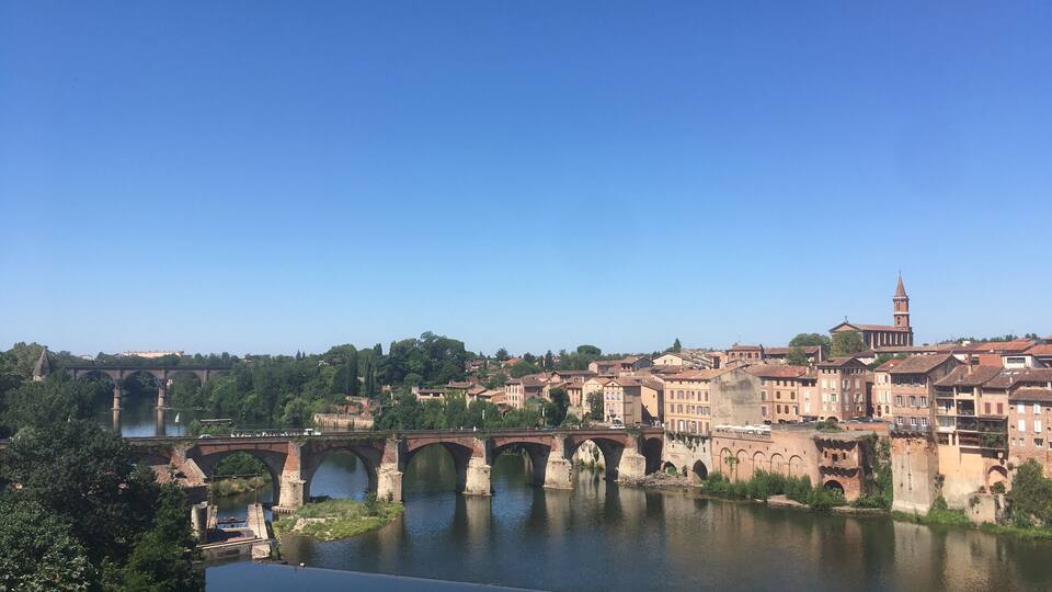 A historic bridge over a river, surrounded by old buildings and a prominent tower.