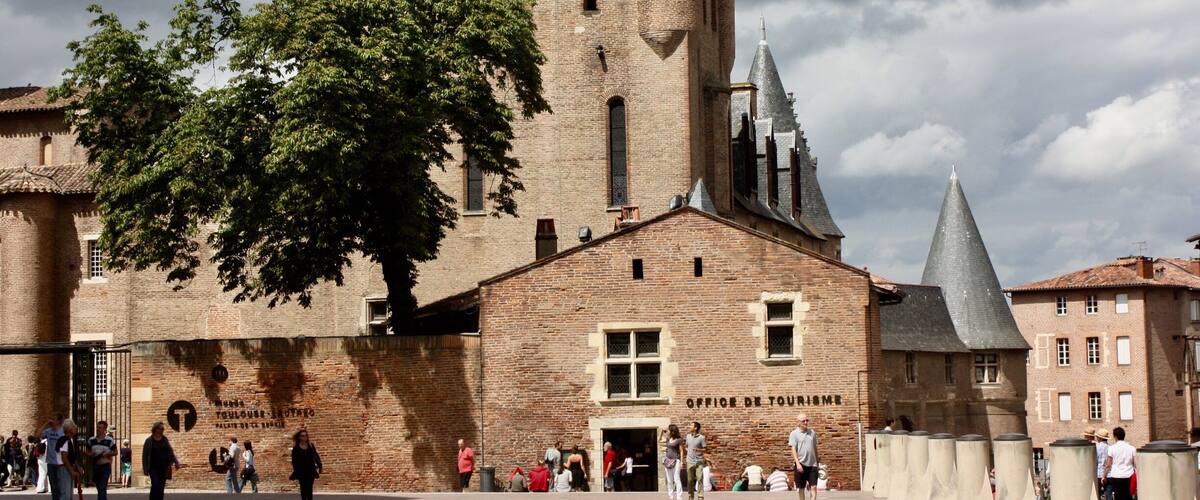 A historic building with a prominent tower and a sign reading "OFFICE DE TOURISME".