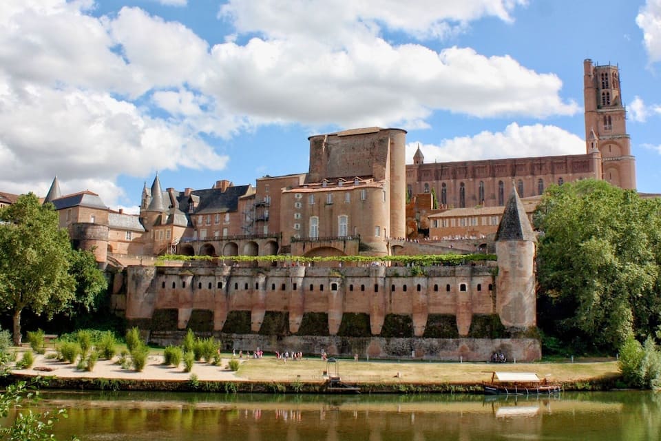 Un castello storico con un fiume in primo piano e un cielo sereno.