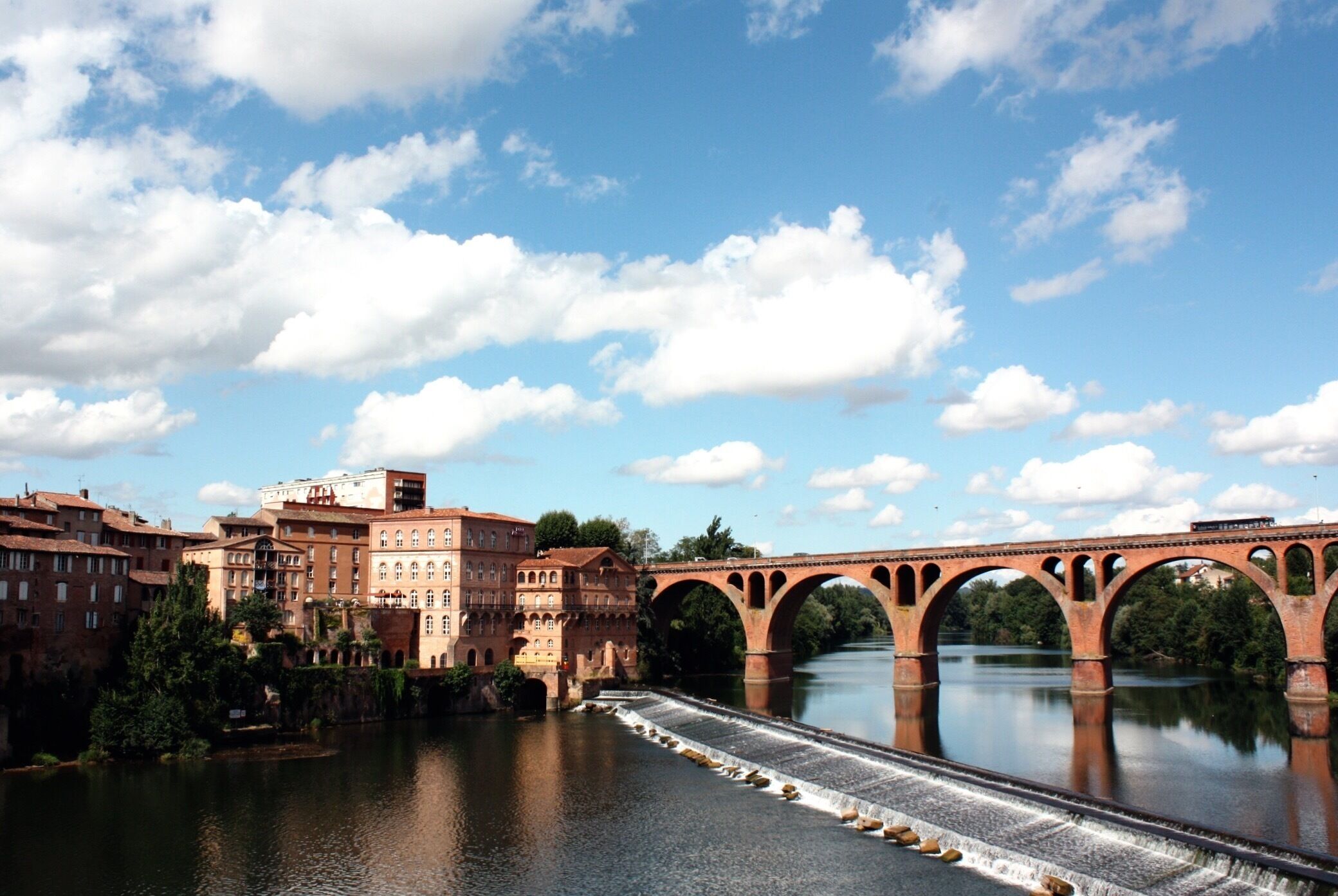 A river with a bridge, buildings, and a clear sky.