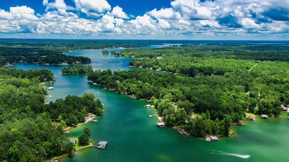 A river winding through a densely forested area with several small docks and boats.