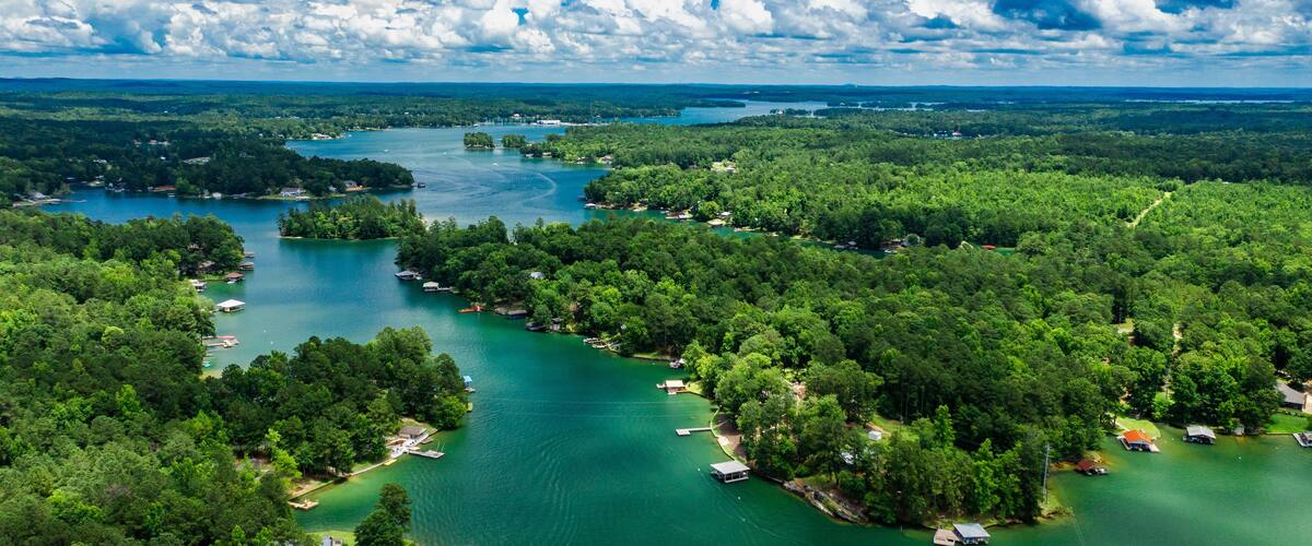 A river winding through a densely forested area with several small docks and boats.