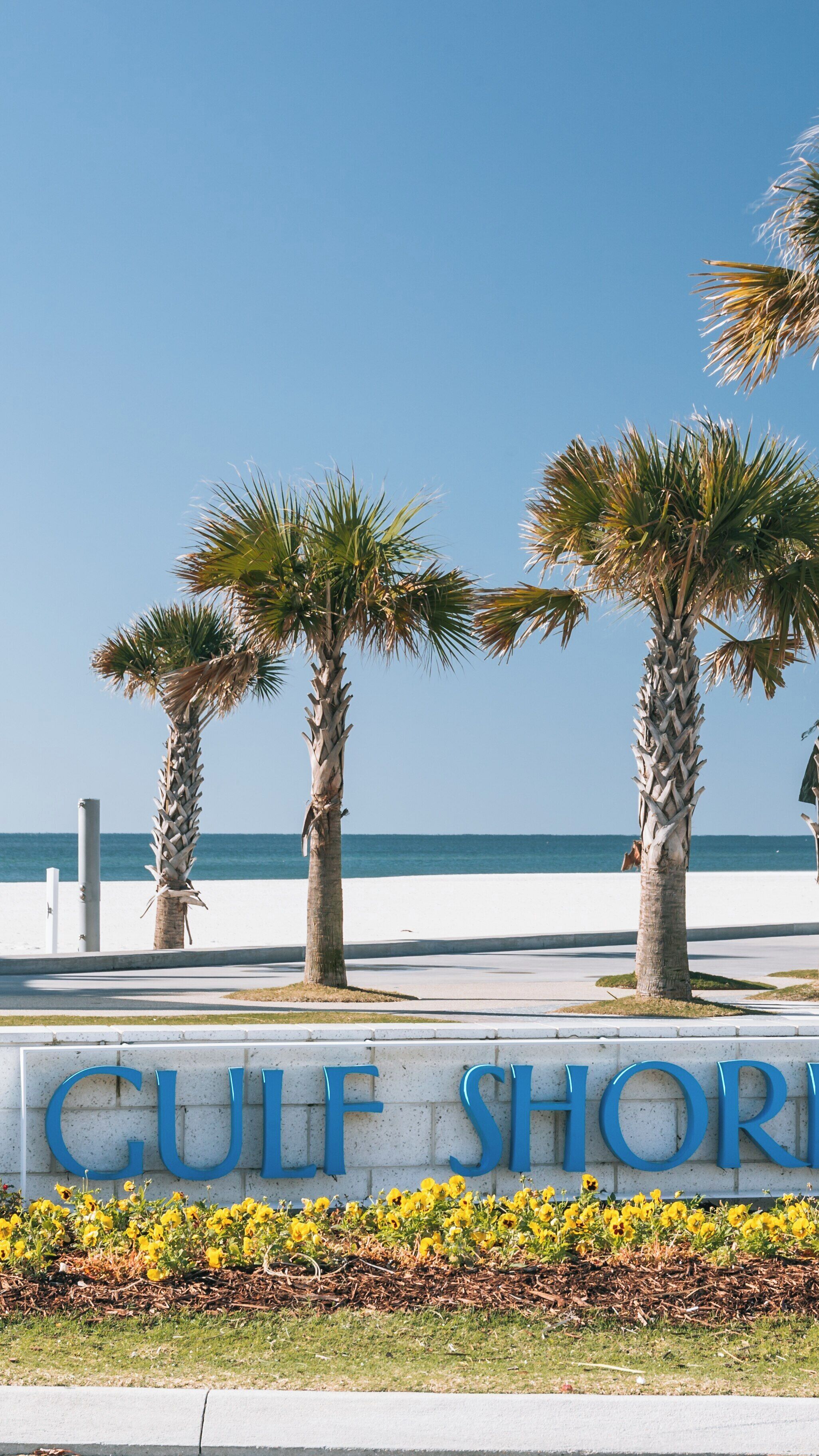 Visit Gulf Shores Beach in Alabama for sun, sand, and stunning ocean views while relaxing under palm trees in warm weather