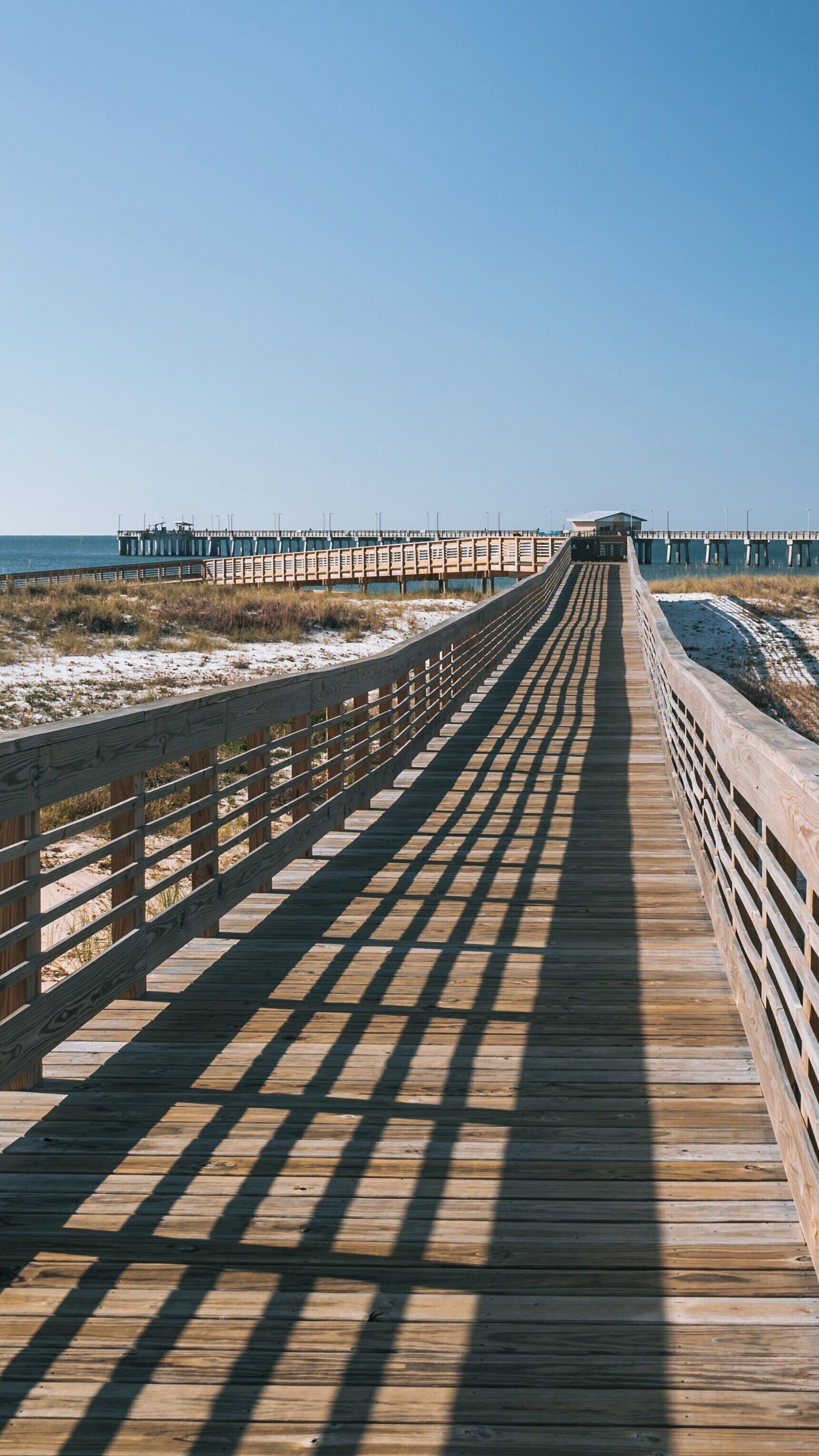 Fishing pier extends into the serene waters of Gulf State Park in Orange Beach, Alabama on a bright sunny day