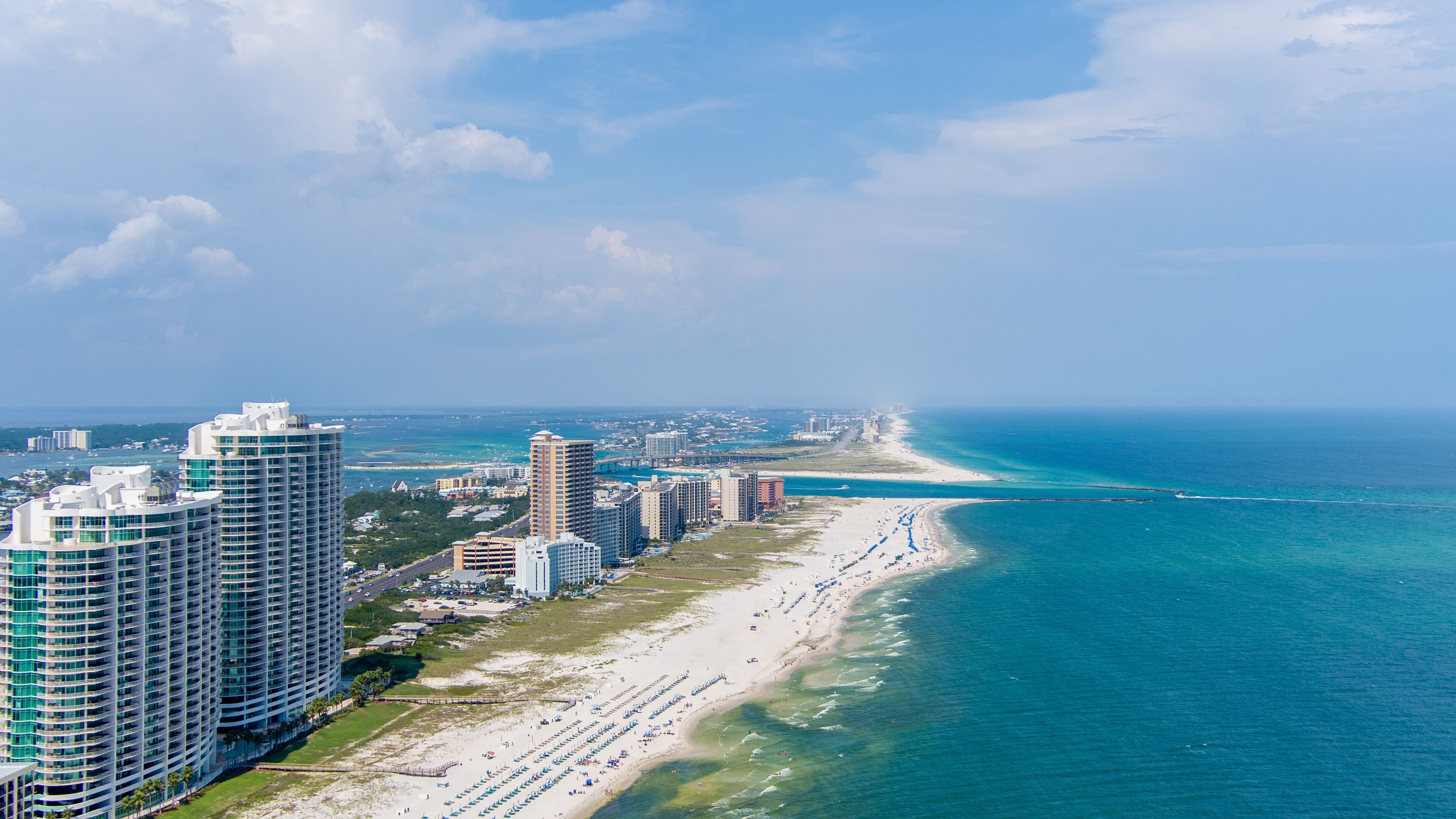 Paisagem costeira com edifícios altos e uma extensa praia de areia.