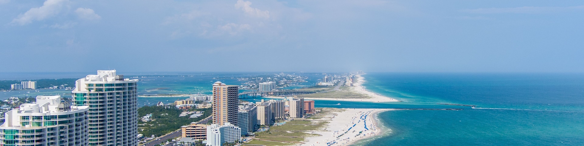 Paisagem costeira com edifícios altos e uma extensa praia de areia.