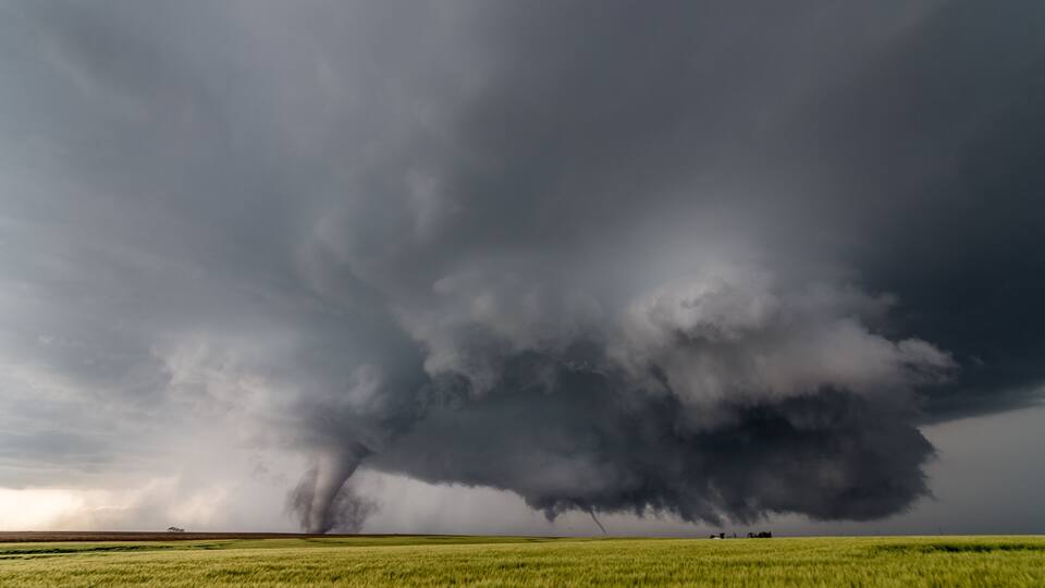 A tornado in a grassy field under a stormy sky.