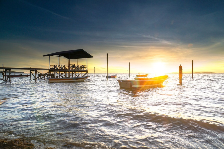 Une jetée dotée d’un espace de repos abrité et d’un bateau amarré au moment du coucher du soleil.