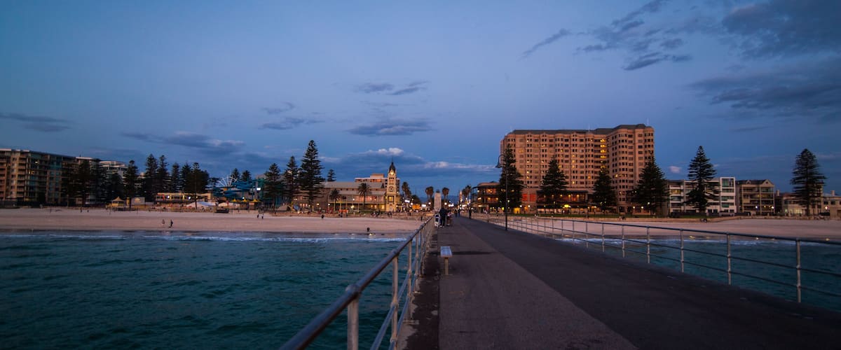 A coastal promenade with a beach, ocean, and buildings in the background.