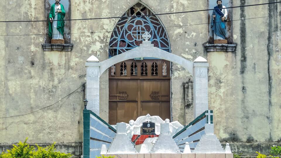 A church with two statues, a Gothic window, and a memorial monument.