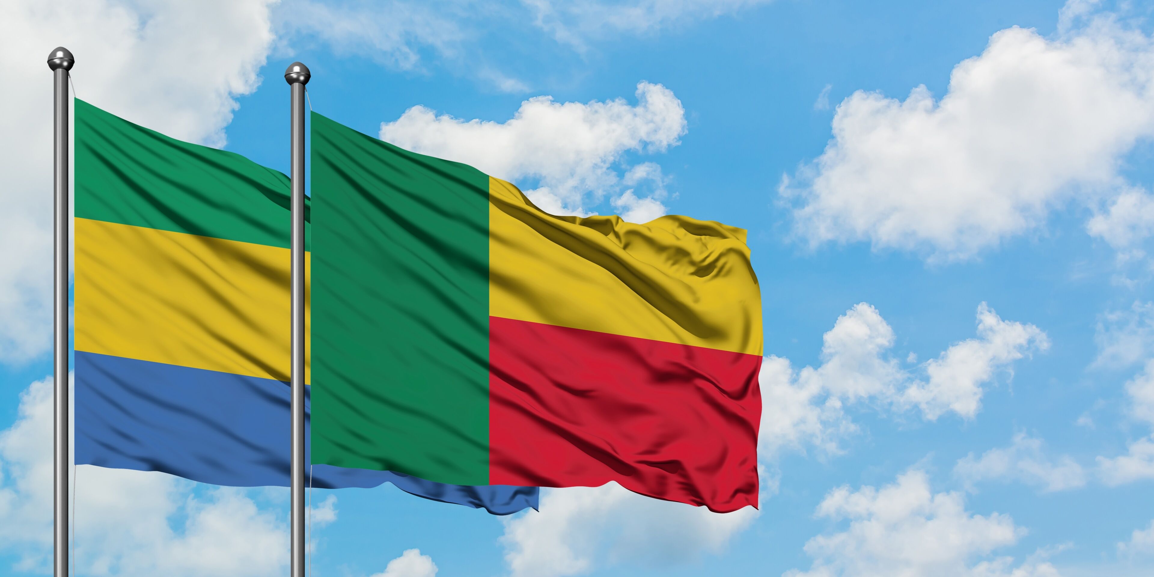 Gabon and Benin flag waving in the wind against white cloudy blue sky together. Diplomacy concept, international relations.
