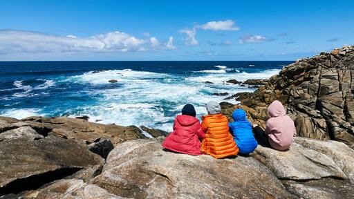 Four people staring at the sea at the Coast od Death, Laxe, Spain