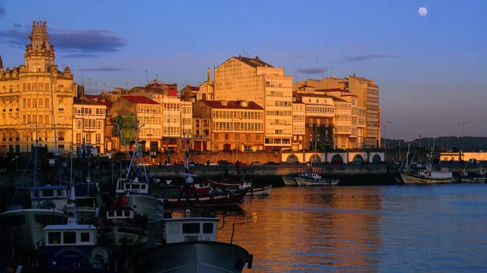 A harbor with boats and buildings at sunset.