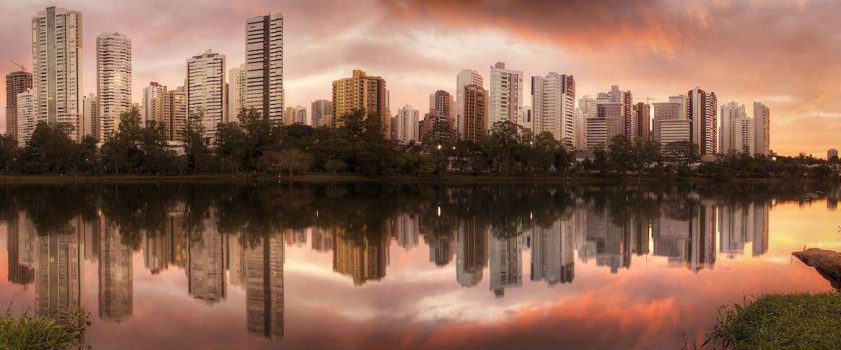 A city skyline reflected in a calm lake at sunset.