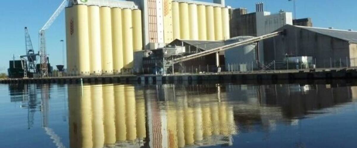 A grain silo complex by a calm water body.
