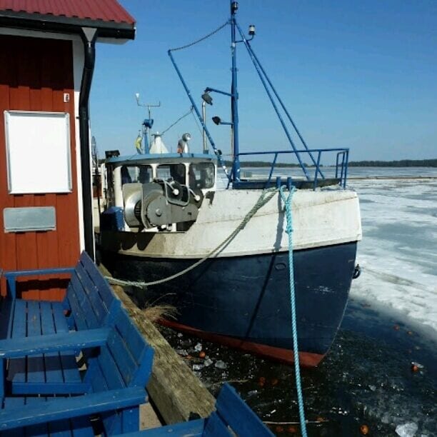 A boat docked at a wooden pier with a clear blue sky in the background.