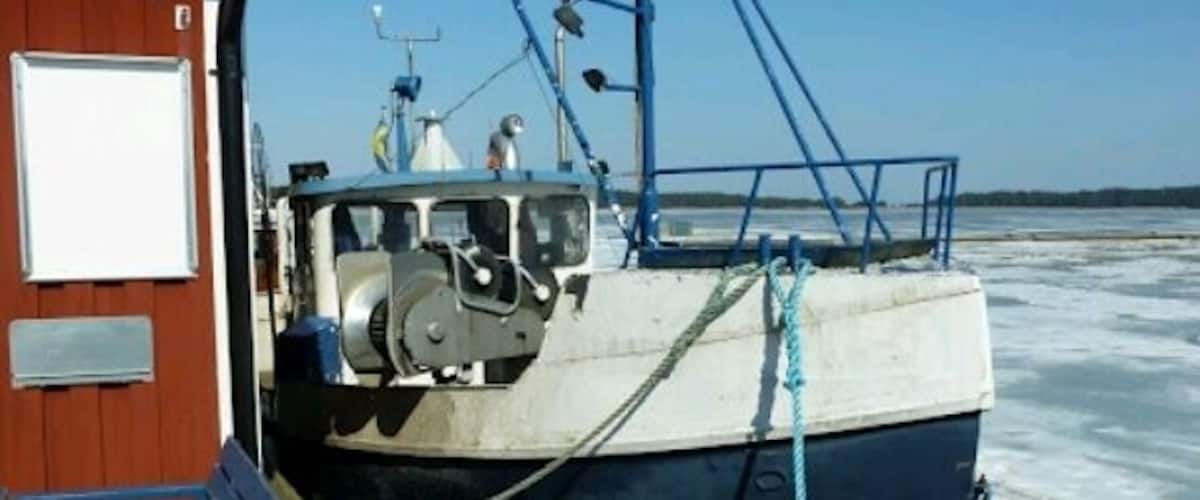 A boat docked at a wooden pier with a clear blue sky in the background.