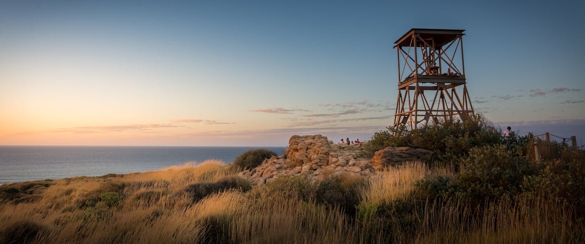 A coastal lookout tower with a clear view of the ocean at sunset.