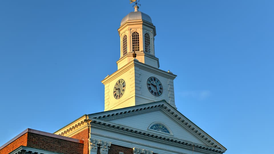 A church with a clock tower, a dome, and a weather vane.
