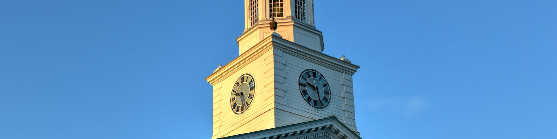 Uma igreja com uma torre de relógio, uma cúpula e um girassol.