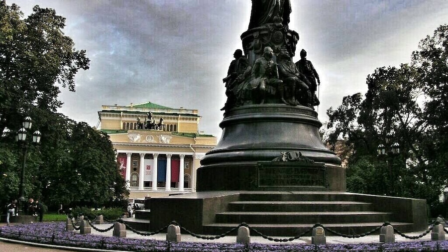 Source: http://www.saint-petersburg.com/monuments/catherine-the-great/
This monument to Catherine the Great was unveiled in 1873. The Empress was adored by the people of St. Petersburg for all her efforts to improve the life and education provided by the city and her reign has long seen been known as the "golden age" of Russia. The statue of Catherine is surrounded by delicately carved figures of the most prominent individuals of her reign: politicians and poets, military men and courtiers. The monument is located in the middle of a small, grass-covered square, just off Nevsky Prospekt, which is lined by the Anichkov Palace, the Alexandrinsky Drama Theater and the Russian National Library. As one of the country's most enlightened monarchs, Catherine could not have chosen a better spot herself.
The monument was designed by the Russian artist M.O. Mikeshin and created by the best sculptors and architects of the day. Catherine the Great is dressed in her official gown and holds a scepter in her right hand and an olive wreath in her left hand. The pedestal is decorated with the symbols of royal power. Among the dignitaries, who's likenesses have been carved on the statue's pedestal, are Alexander Suvorov, perhaps the most famous general in Russian history, Prince Potiomkin, the general and politician, Ekaterina Dashkova, the first woman to chair the Russian Academy of Sciences