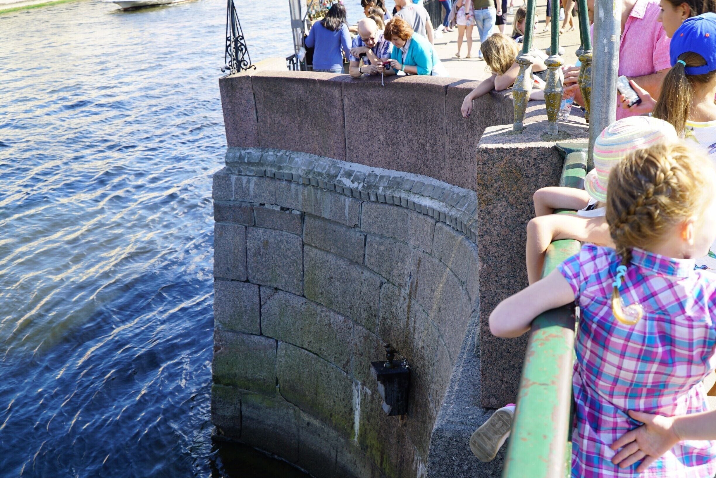 People dropping coins on a ledge on the wall, or at least trying to, presumably to gain good luck or fortune.  Most of the coins were falling into the water of course.
