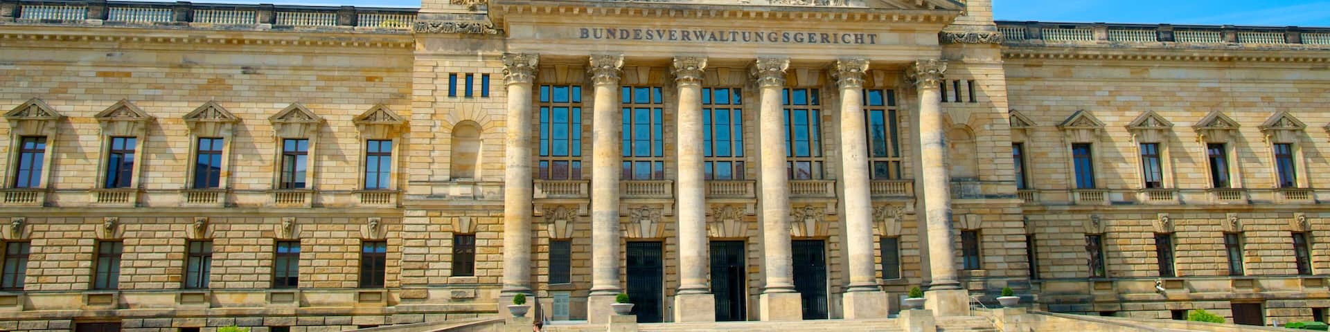 A large, historic building with a prominent dome and two smaller domes, featuring classical architecture and columns.