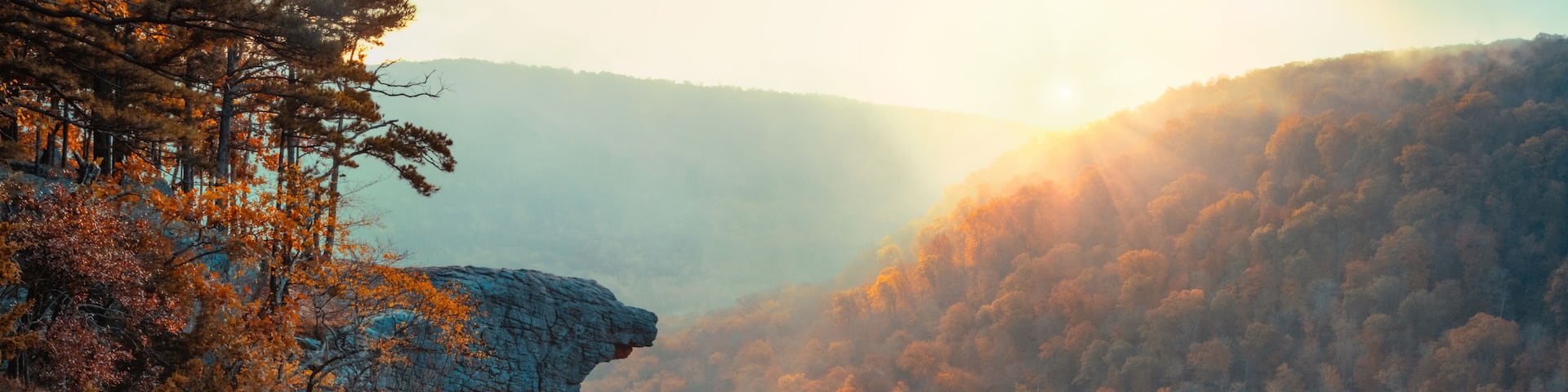 A mountainous landscape with autumn foliage and a rocky cliff.