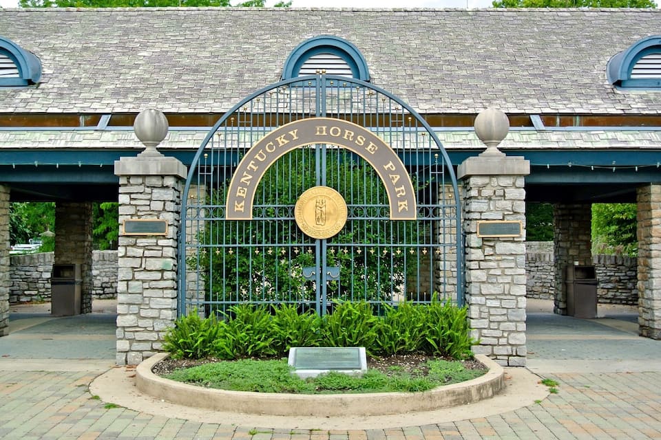 A Kentucky Horse Park entrance with a stone archway, a gold emblem, and a plaque.