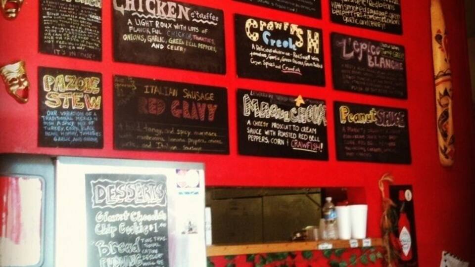 A wall with various food items listed, including 'Traditional Jambalaya', 'Gumbo', 'Red Beans', 'Chicken', 'Italian Sausage', and 'Peanut Pie'.