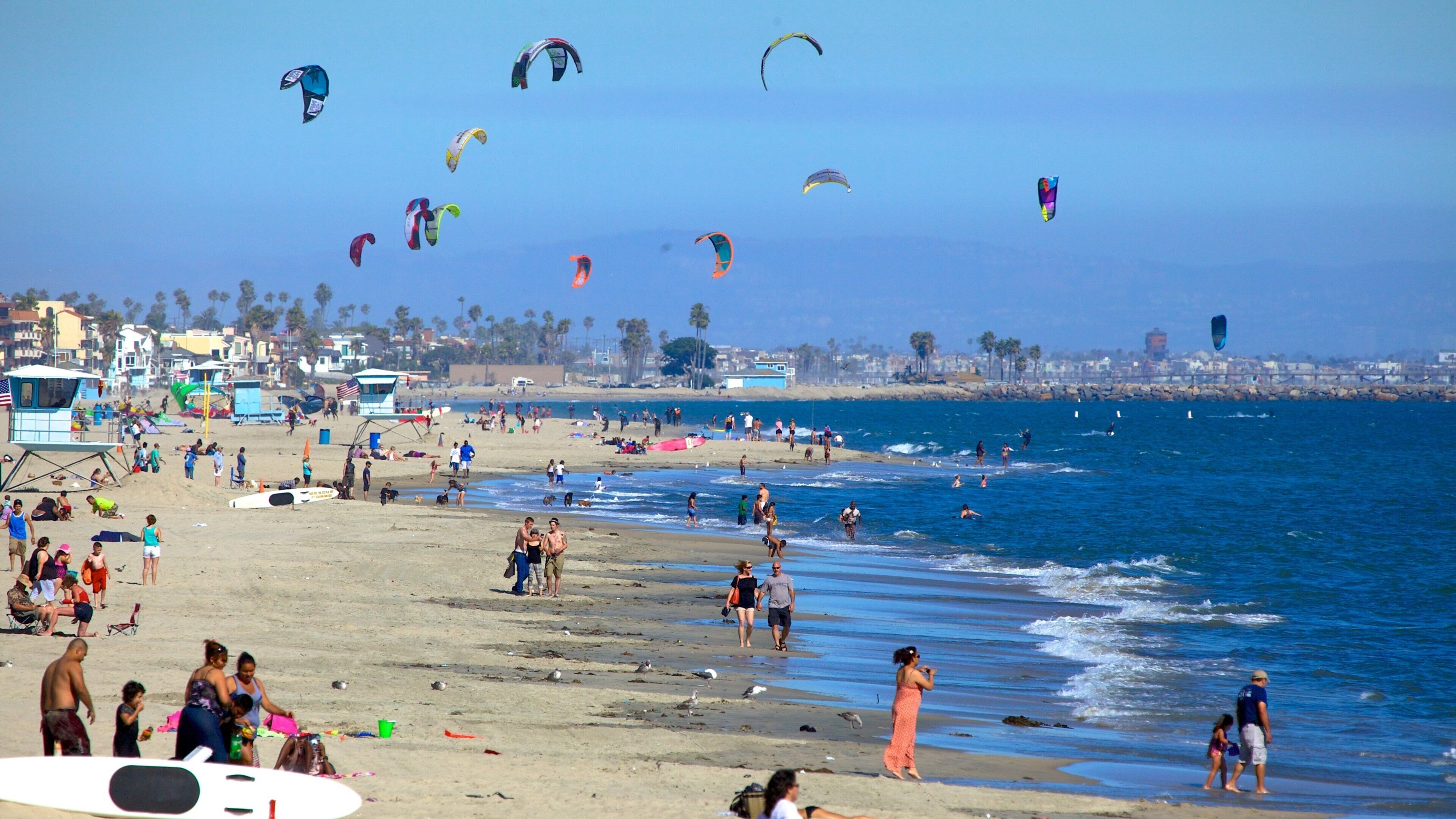 A beach with people, kites, and a lifeguard tower.