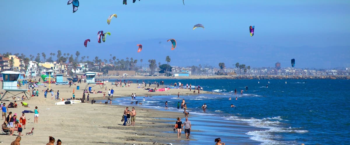 A beach with people, kites, and a lifeguard tower.
