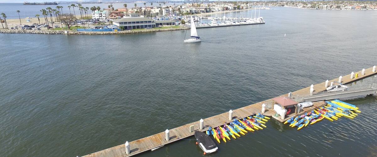A marina with boats, a sailboat, and a dock with kayaks.