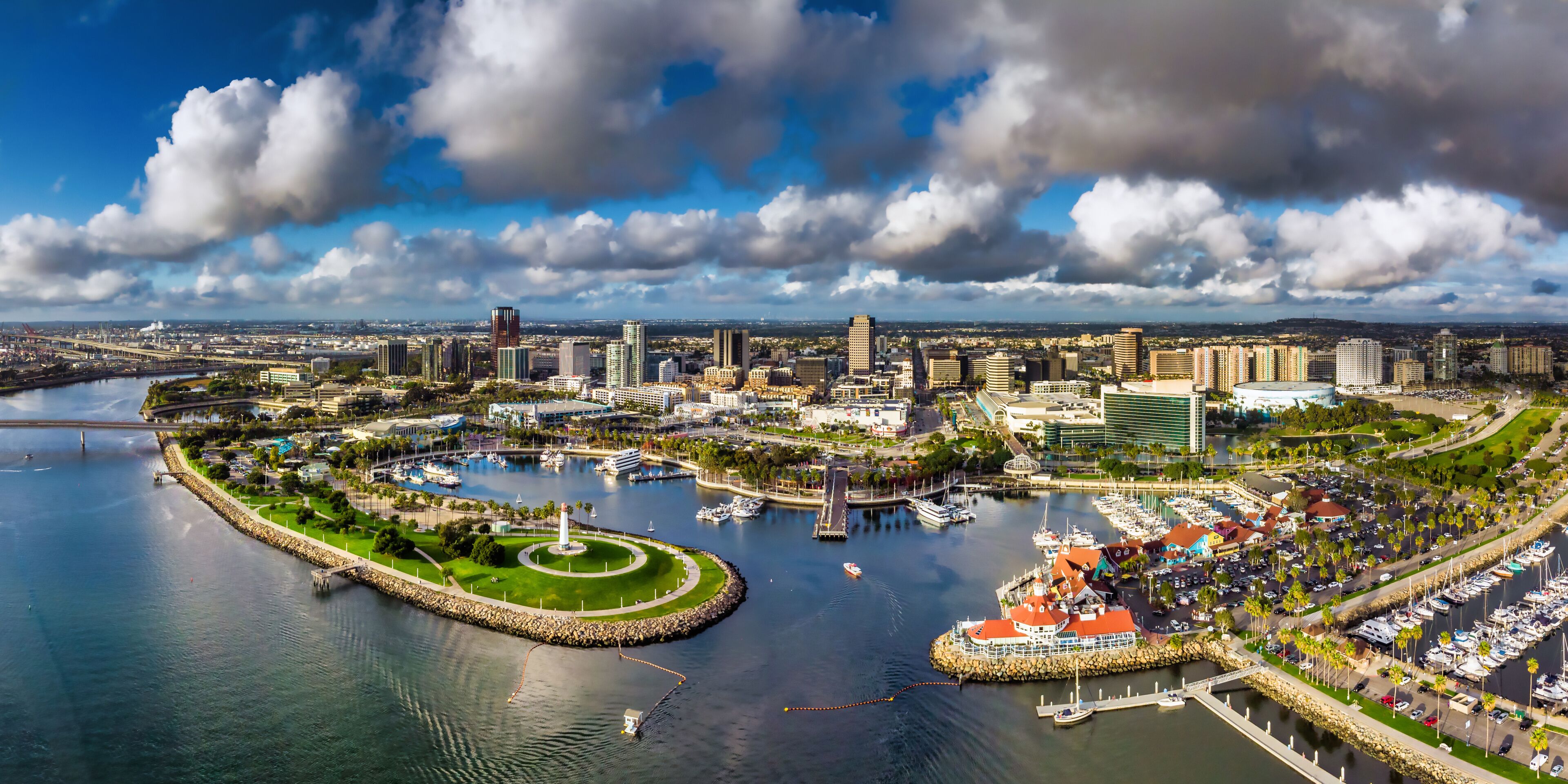 A coastal cityscape with a marina, a circular park, and a prominent tower.