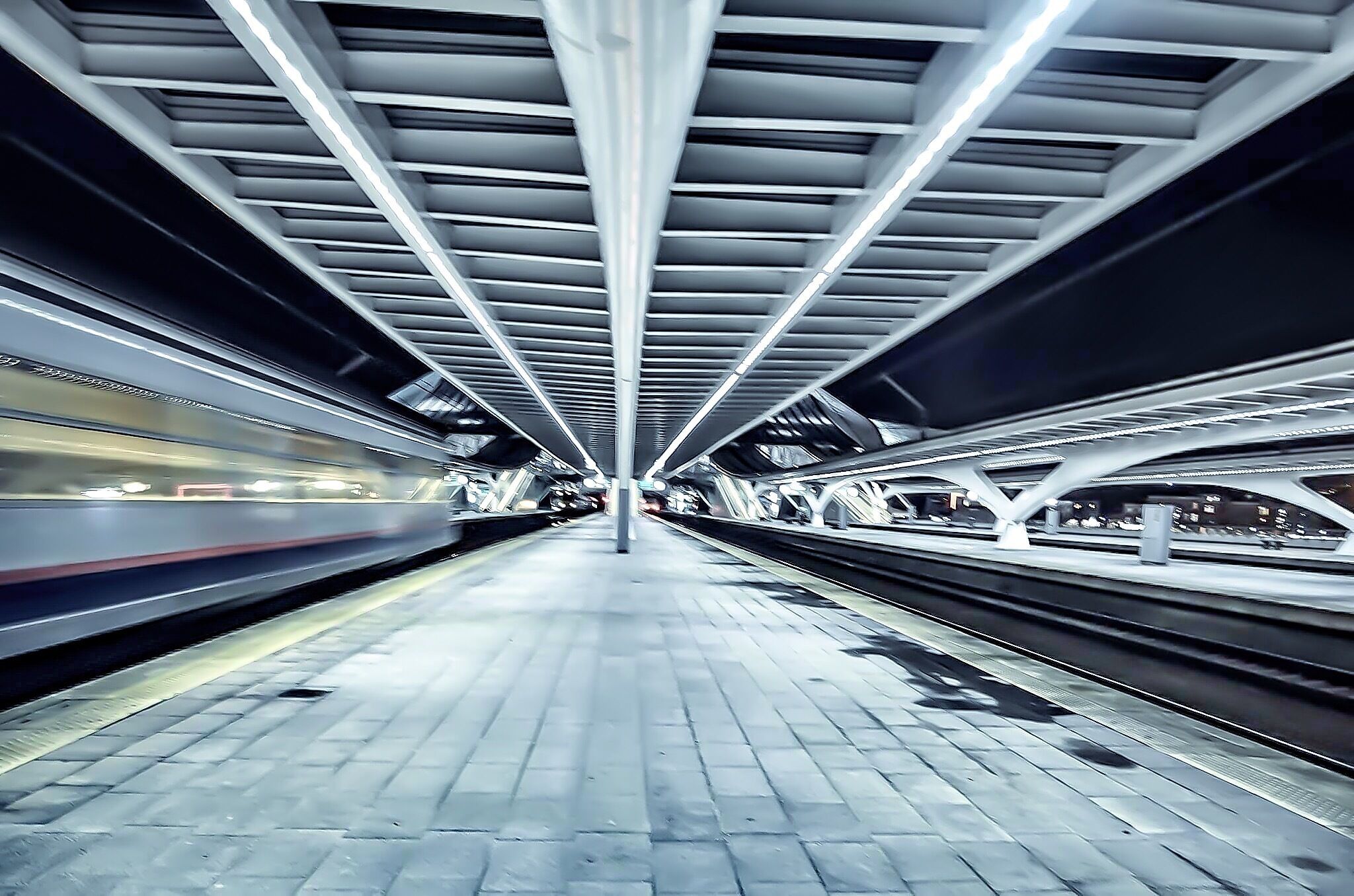 A modern train station with a sleek, metallic ceiling and a long platform.