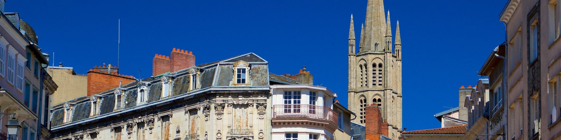 Una calle histórica con edificios ornamentados y una alta aguja de iglesia.