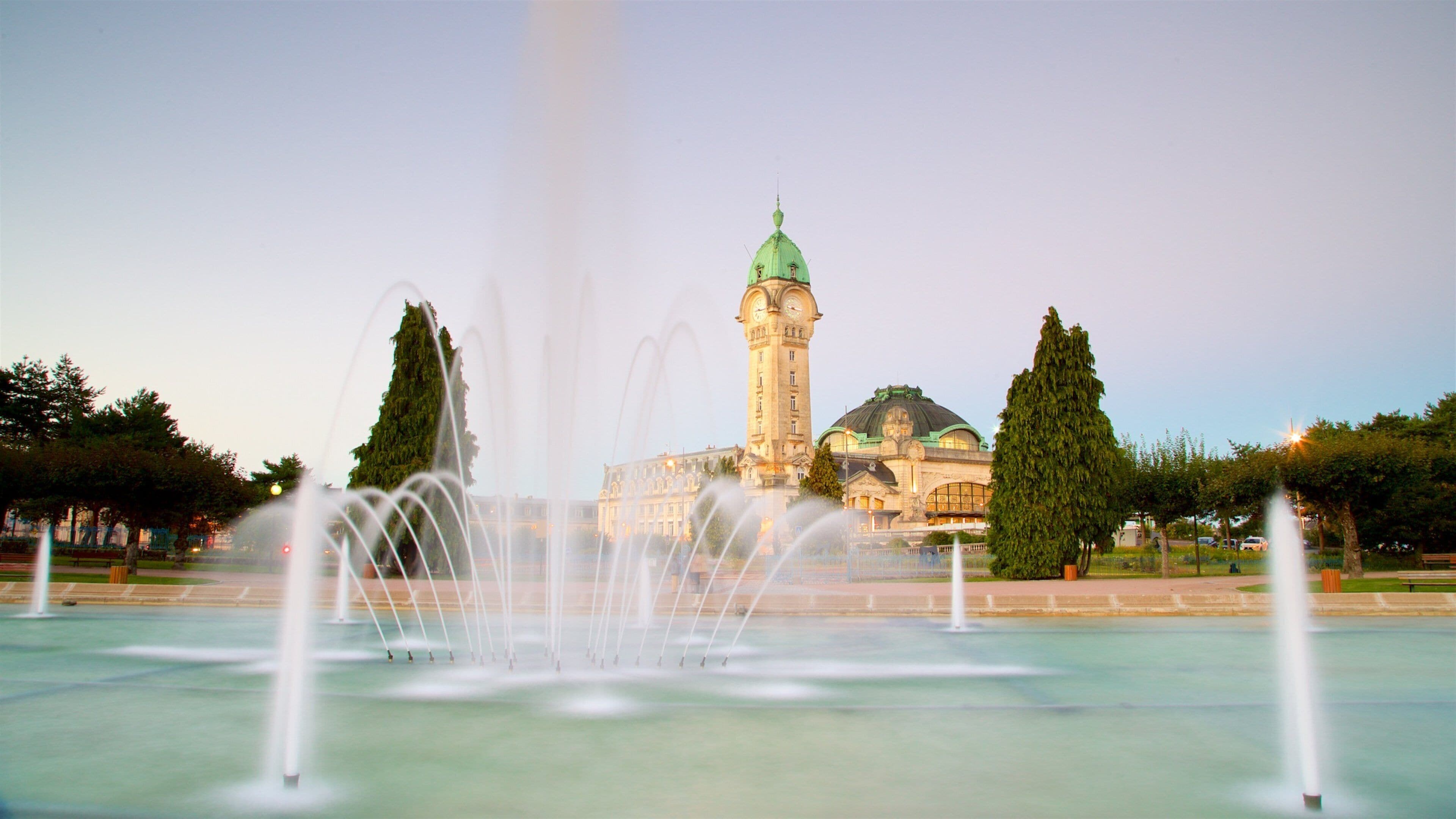 A historic building with a clock tower and a fountain in the foreground.