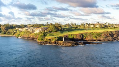 A coastal landscape with a golf course, a lighthouse, and residential buildings.