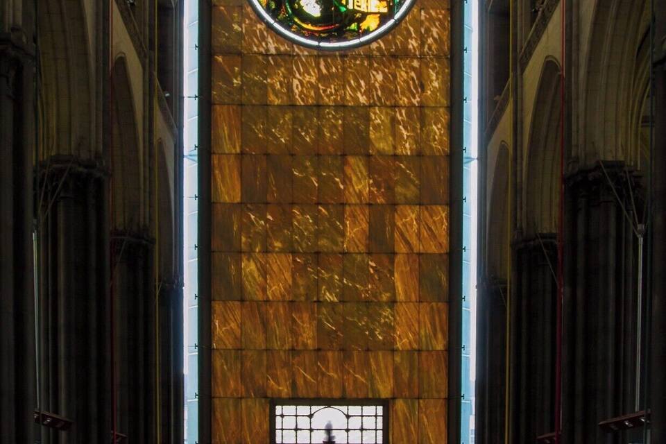 A church interior with a large stained glass window and rows of pews.