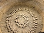 A circular arrangement of skulls and bones in a brick structure.