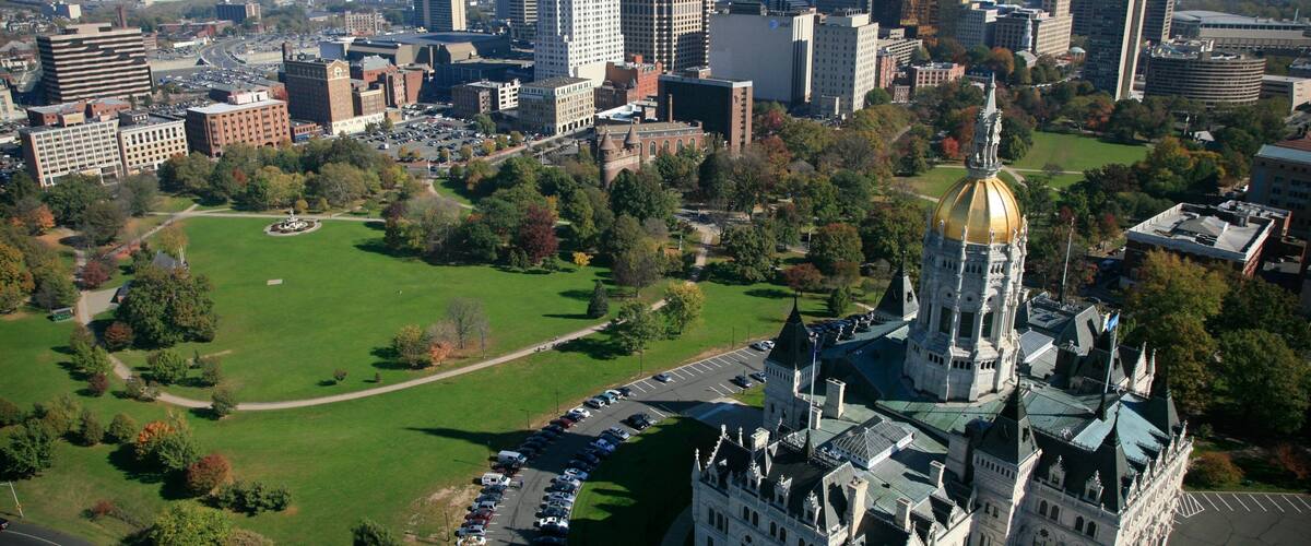 A cityscape with a prominent historic building with a golden dome, surrounded by green spaces and modern high-rise buildings.