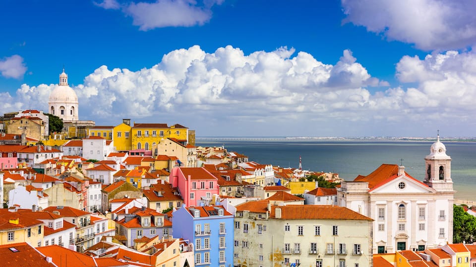 A coastal cityscape with colorful buildings and a prominent white dome structure.