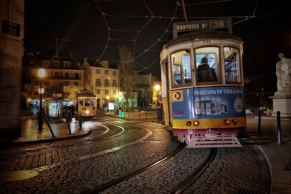 A tram on a cobblestone street at night.
