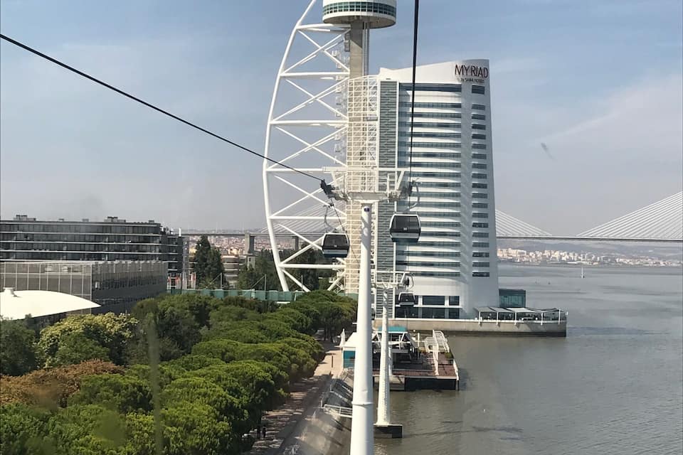 A Ferris wheel, a modern building, and a river.